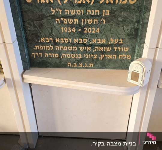 מצבה עם כיתוב בעברית על רקע שיש ירוק